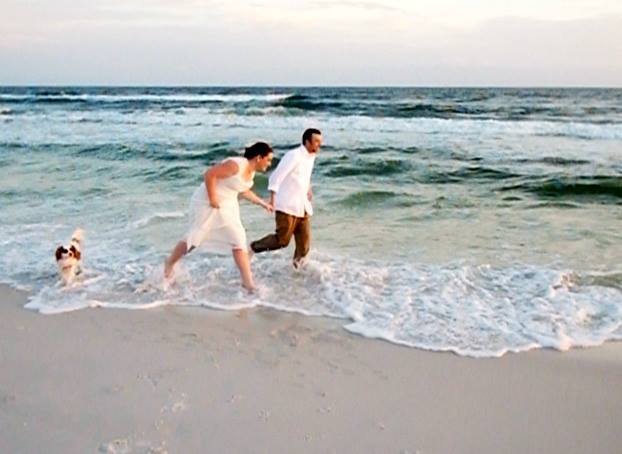 This happy couple and their dog, enjoy a run in the surf after the wedding ceremony.