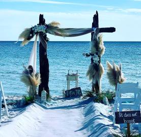 Driftwood Arbor with Pompous Grass and 30 white Padded Chairs, Sand Ceremony Table & Corinthians 13 verses 4 -7 signs